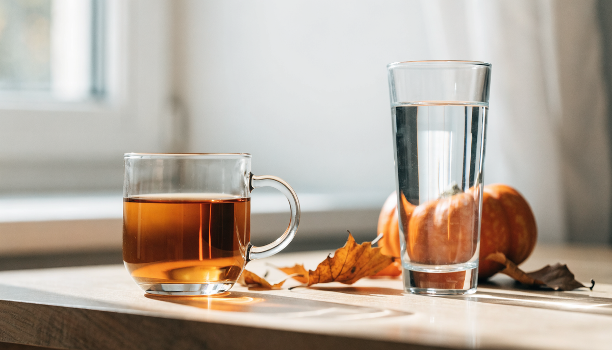 Boisson chaude et verre d'eau sur une table en bois avec des feuilles d'automne