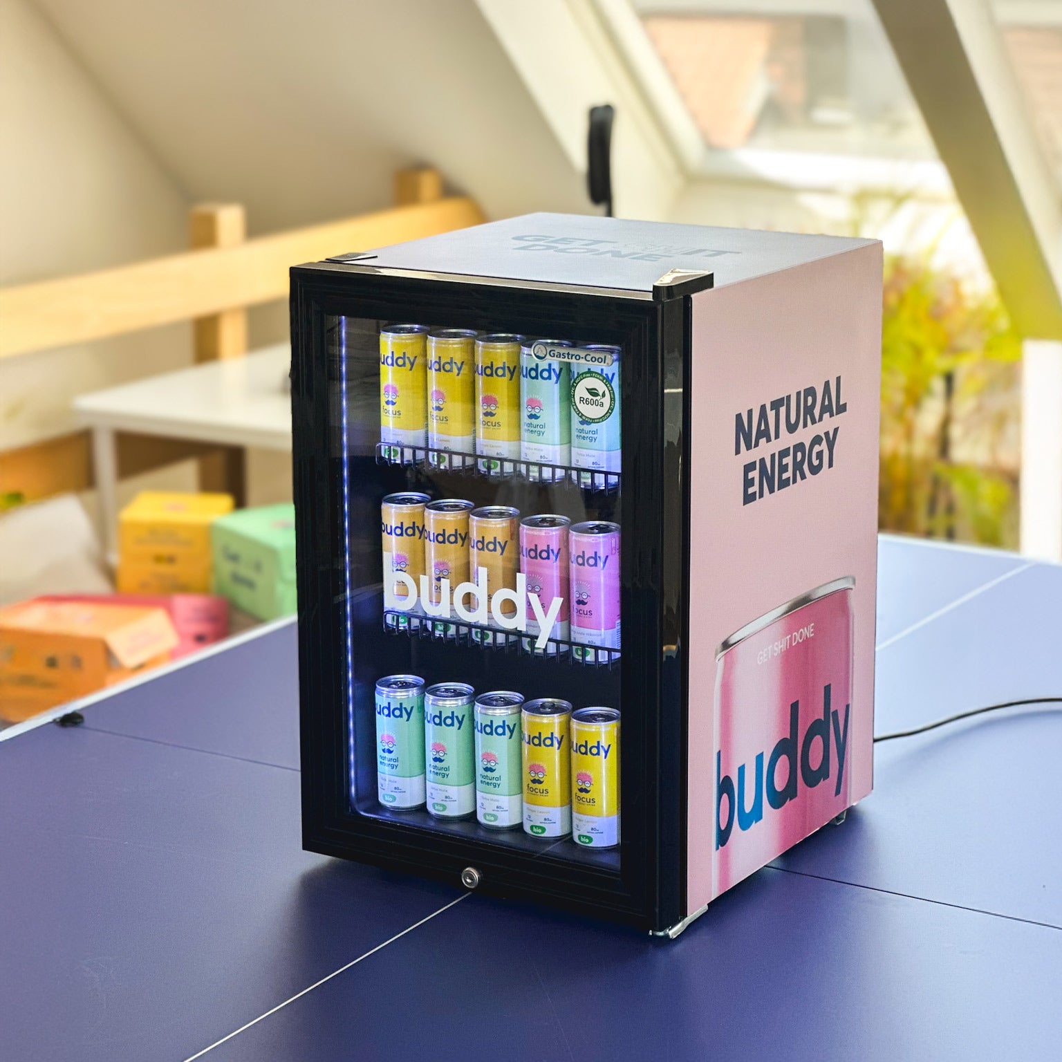 Mini frigo Buddy noir et rose contenant des canettes de boissons énergisantes naturelles bio – slogan “Natural Energy” visible sur le côté