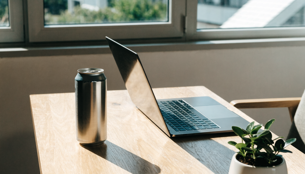 Canette de boisson posée sur un bureau lumineux avec un ordinateur portable